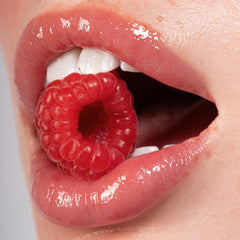 Close-up of a mouth with a raspberry inside