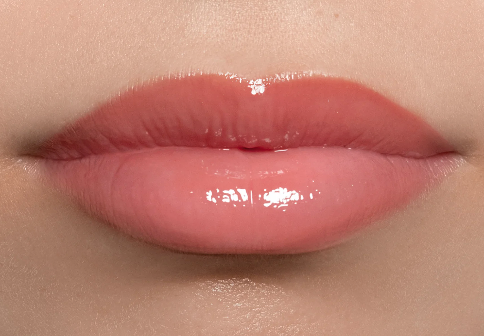 Close-up of glossy pink lips on a beige background