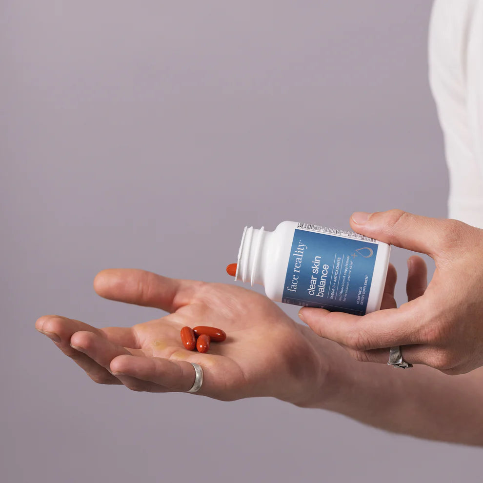 Person holding a supplement bottle and pills on an open palm against a gray background